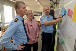 Ein Soldat und eine zivil gekleidete Frau erklären einem weiteren Soldaten etwas.