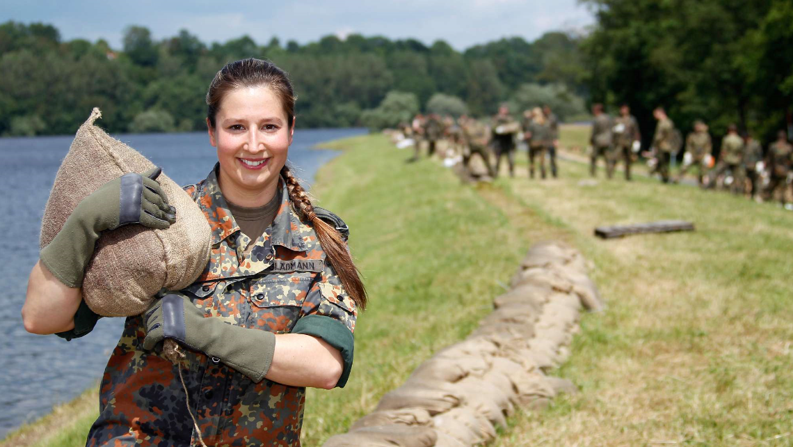 Eine Soldatin beim Dammbau mit Sandsäcken