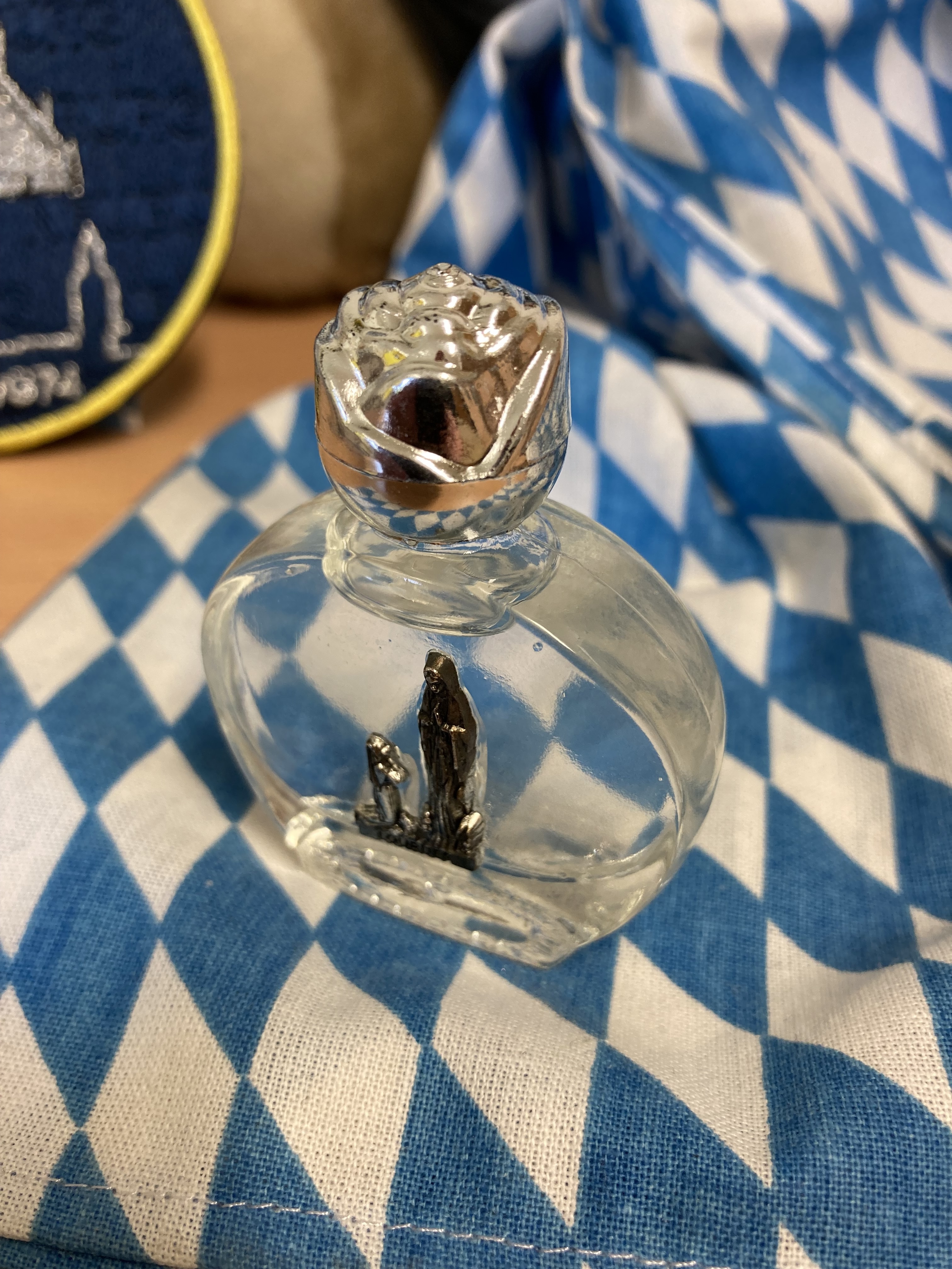 Fläschchen mit Lourdeswasser auf einem blau-weißem Tuch