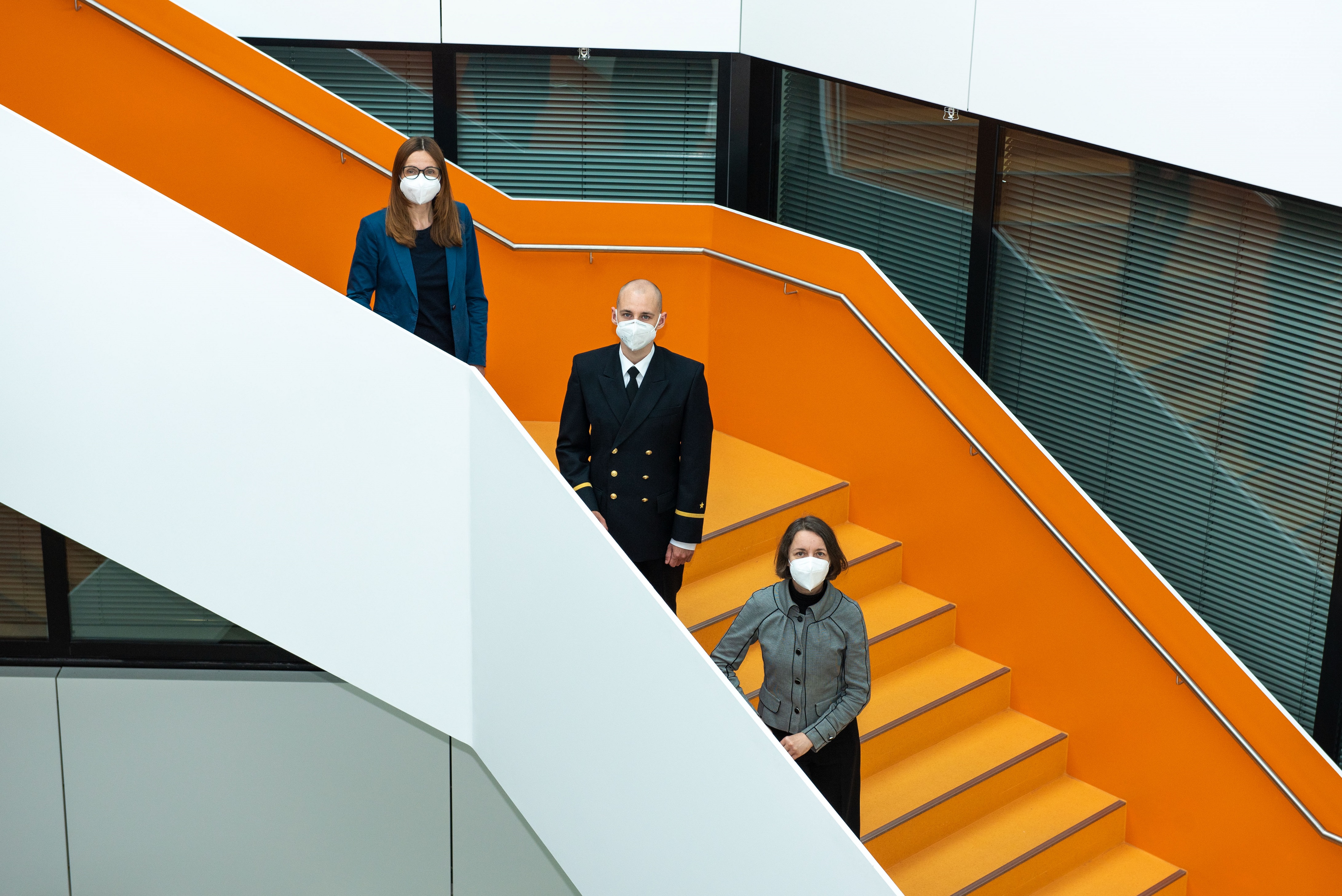 Frauen und Männer, in Zivil und in Uniform, stehen auf einer Treppe