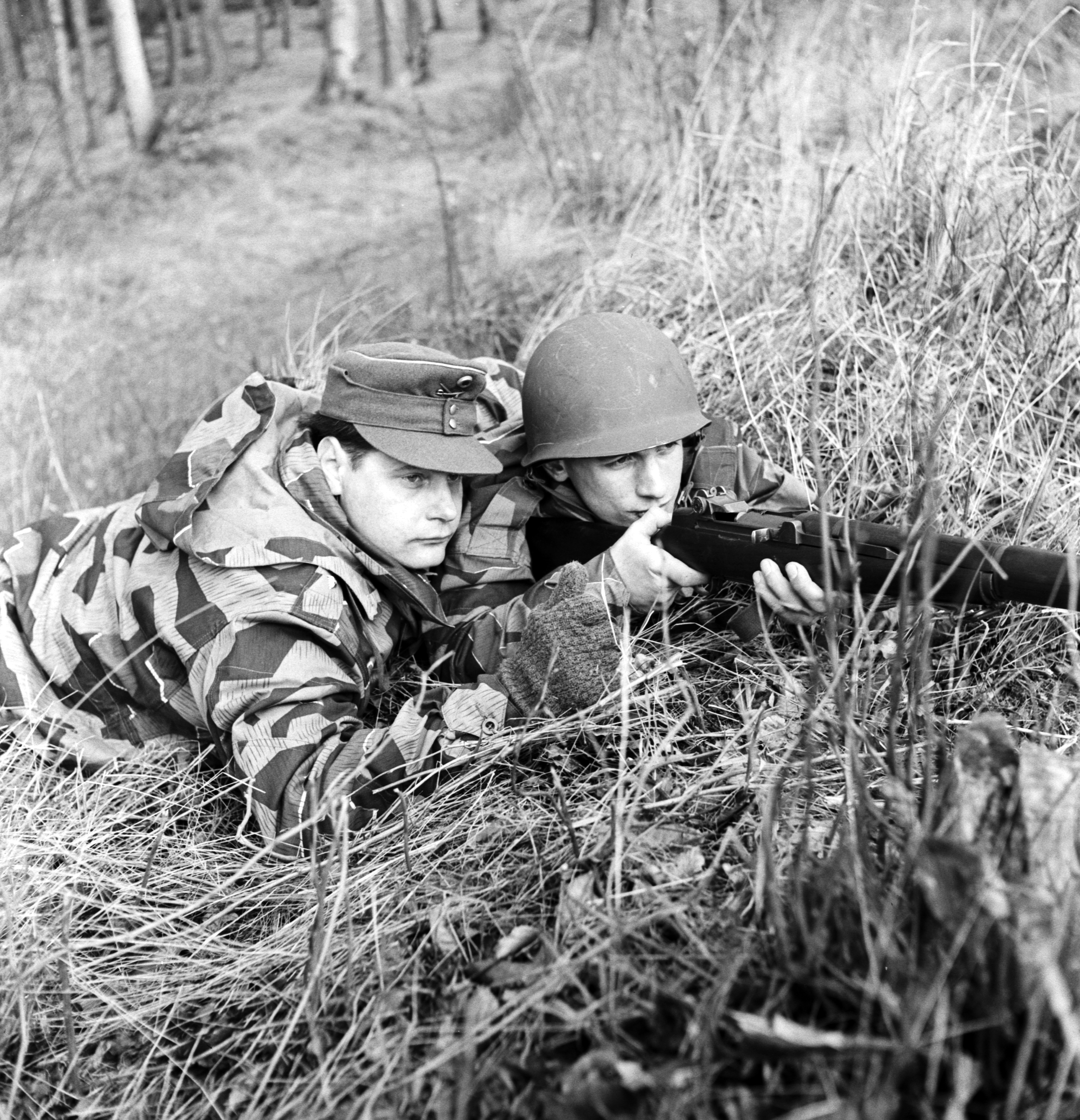 Zwei Soldaten liegen mit einem Gewehr in einer Wiese
