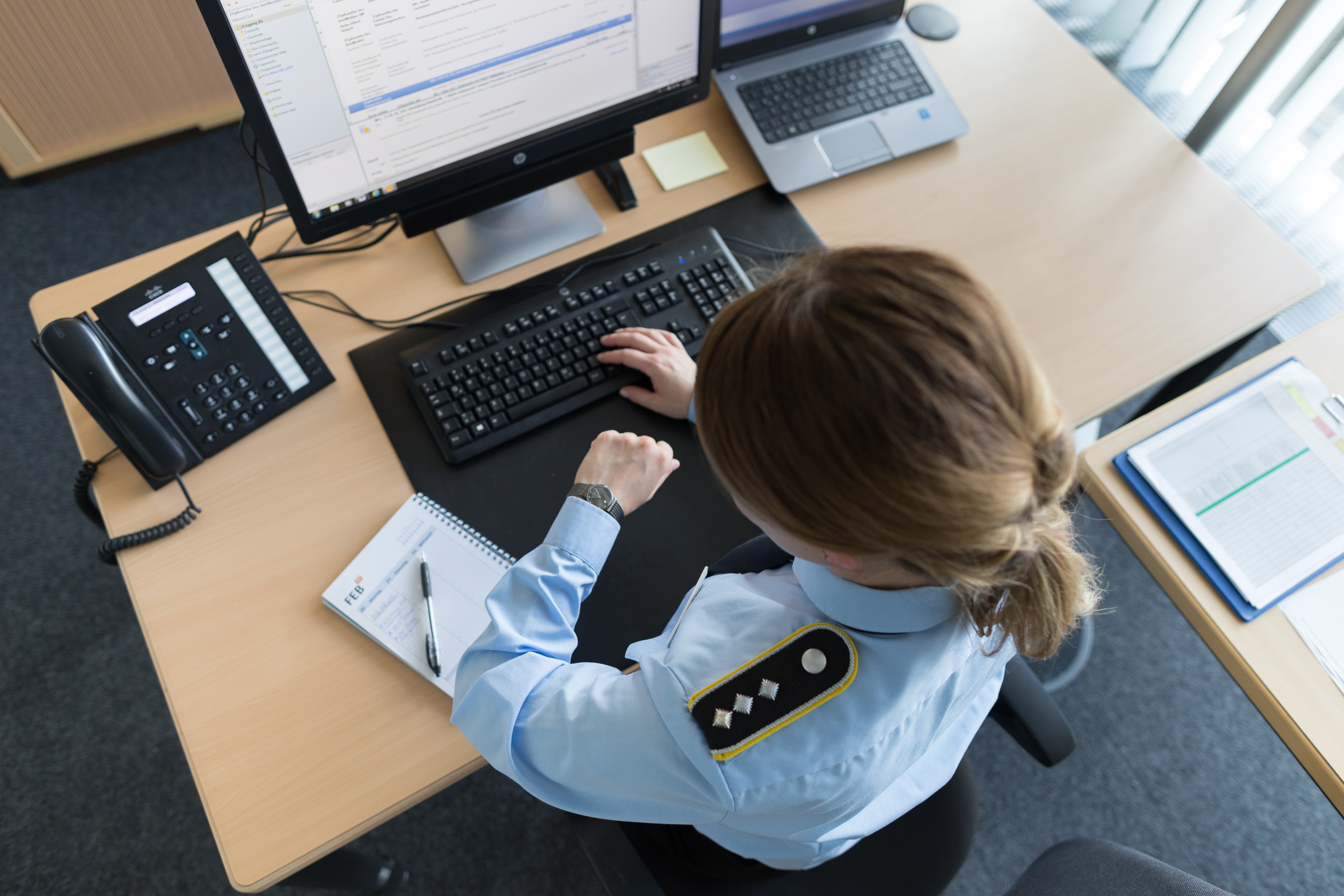 Eine Soldatin sitzt vor ihrem Laptop und schaut auf die Uhr