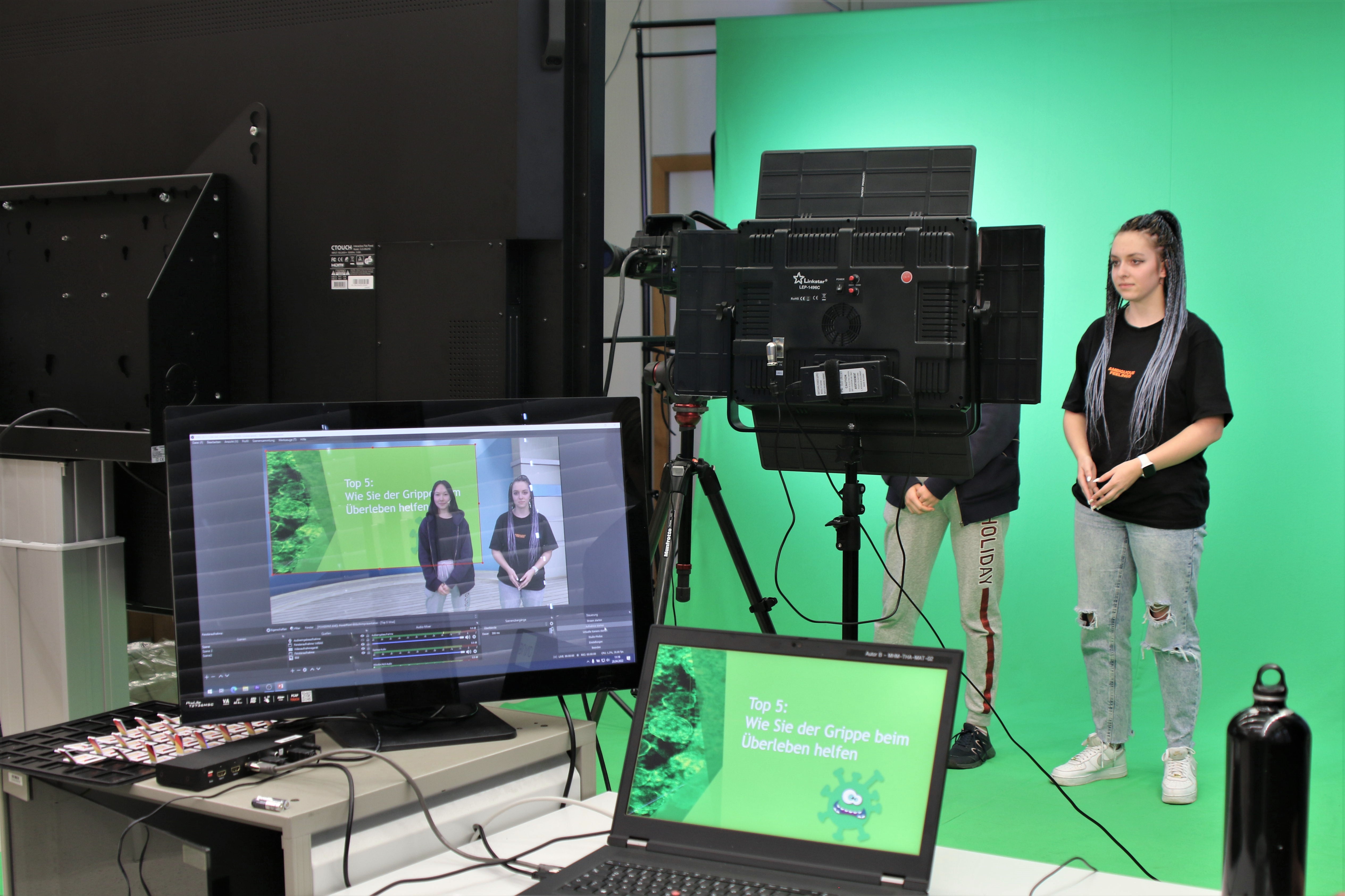 Zwei junge Frauen stehen in einem Videostudio vor einem Greenscreen.