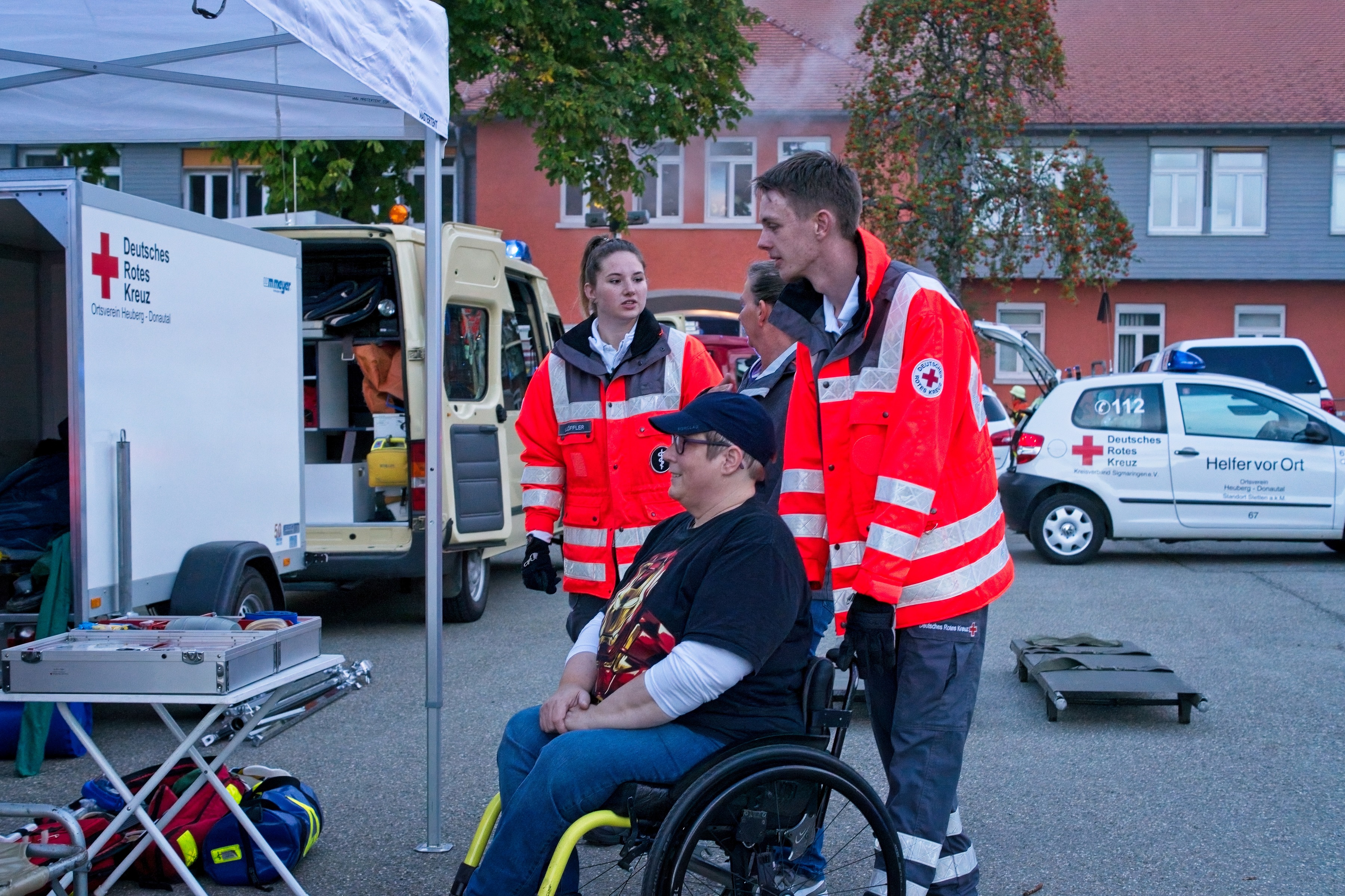 Eine Frau im Rollstuhl wird von Leuten des DRK geschoben