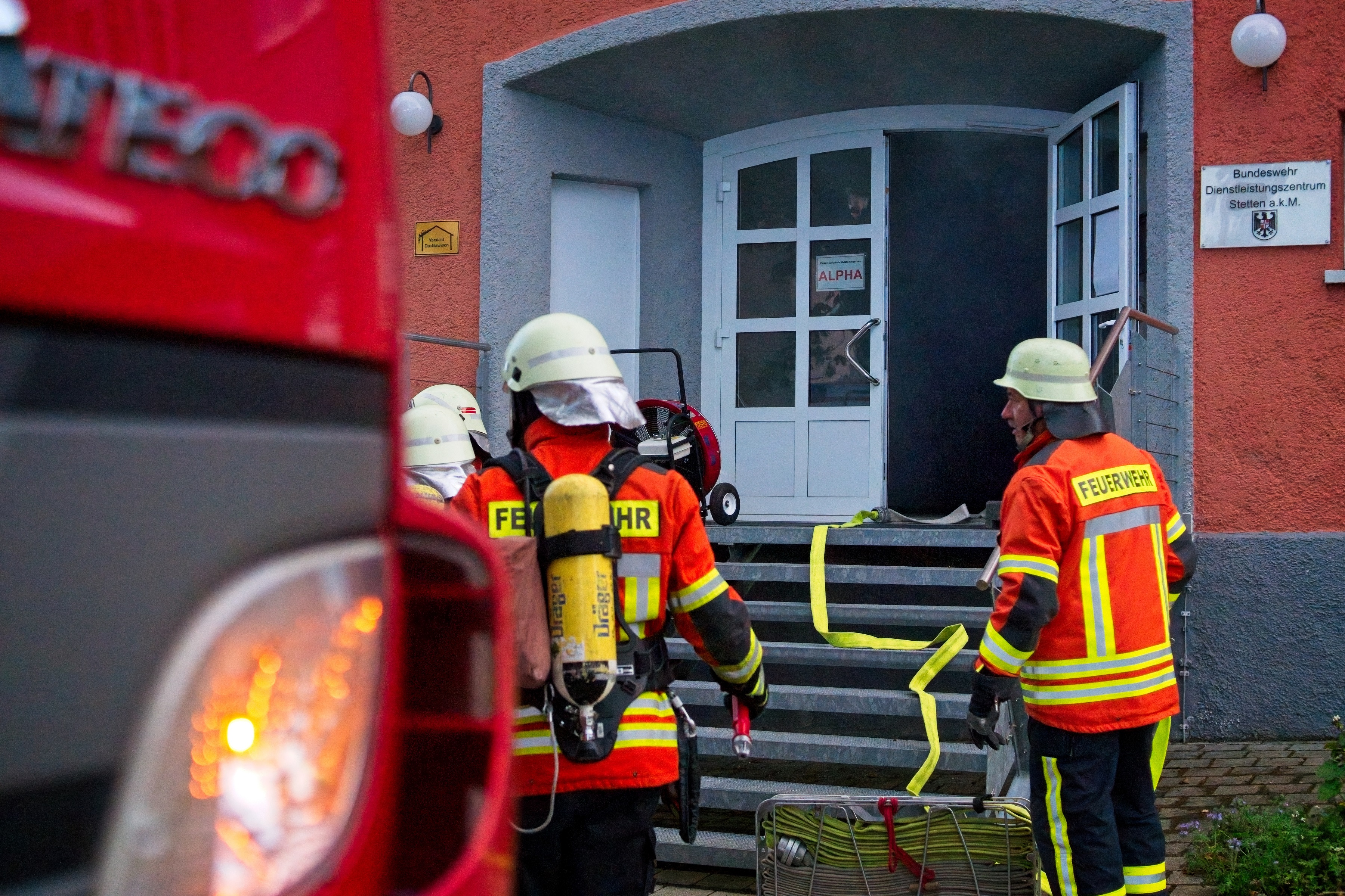 Mehrere Feuerwehrleute vor dem Eingang des verrauchten Gebäudes