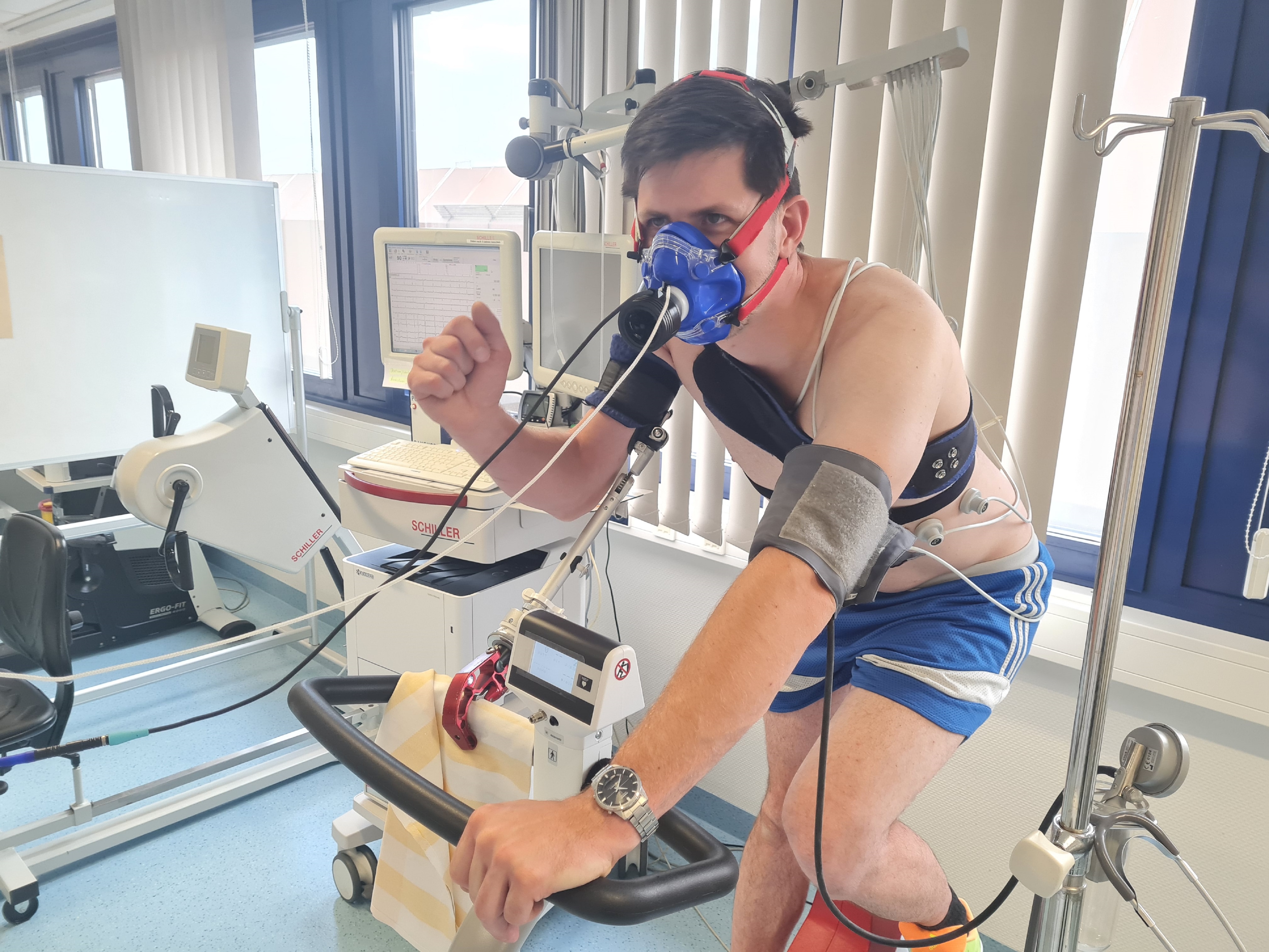 Ein Mann mit einer Sauerstoffmaske sitzt auf einem Ergometer.