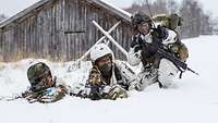 Drei Infanteristen liegen im Schnee in Stellung.