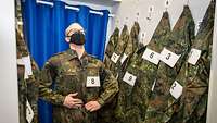 Ein Soldat mit Mund-Nasenschutz probiert eine Flecktarn-Uniform an. 