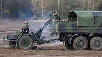 Ein Soldat auf dem Lkw wirft eine Mine in die Rutsche, ein anderer sitzt auf dem angehängten Verlegesystem.