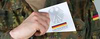 Die Soldaten und Soldatinnen der Bundeswehr sind dem Grundgesetz verpflichtet. Soldat zieht Grundgesetzbuch aus der linken Brusttasche seiner Uniform.