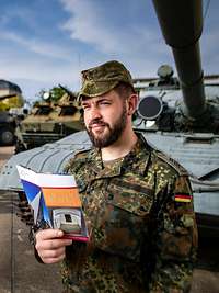 Soldaten auf dem Gelände des Militärhistorischen Museum der Bundeswehr Ein Soldat steht mit einem Flyer in der Hand auf einem Gelände mit mehreren Bundeswehrfahrzeugen und schaut sich um.