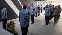 Mehrere Soldaten stehen in vier Reihen vor dem Ehrenmal und grüßen militärisch.