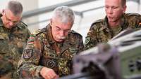 Drei Soldaten stehen hinter einem technischen Gerät.