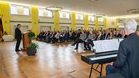 Blick auf Gäste in einem Festsaal, rechts im Vordergrund sitzt Musiker an einem Tasteninstrument