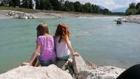 Zwei kleine Mädchen sitzen am Flusslauf