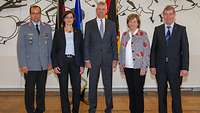 Gruppenbild mit zwei weiblichen und drei männlichen Personen, eine davon in Uniform, in einem Festsaal