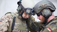 Zwei Soldaten mit Helm halten den Kopf aneinander