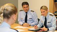 Hauptfeldwebel Johanna Braun und Stabsfeldwebel Sven Schnabel sitzen am Tisch und besprechen sich mit weiteren Crewmitgliedern.