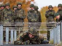 Mannschaften auf der Hindernisbahn Soldat kriecht unter einem Hindernis durch