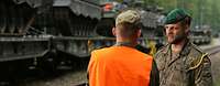 Soldaten der Bundeswehr bei der Fahrzeugverladung Zwei Soldaten im Gespräch, im Hintergrund mehrere Panzer verladen auf Eisenbahnwagen