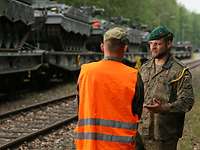 Soldaten der Bundeswehr bei der Fahrzeugverladung Zwei Soldaten im Gespräch, im Hintergrund mehrere Panzer verladen auf Eisenbahnwagen
