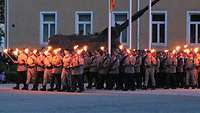 Deutsche und französische Soldaten marschieren mit Fackeln zum Großen Zapfenstreich.