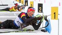 Ein Biathlet der gerade sein Gewehr nachlädt.