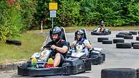 Drei Teilnehmer fahren Go-Kart durch einen Parcour von schwarzen Autoreifen.
