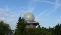 Das Radargerät bei Erndtebrück: Das runde Radom, die Schutzhülle des Radars, ragt über den Baumwipfeln in den Himmel.