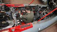 Ein Soldat sitzt im offenen Cockpit eines Tornado und überprüft dort die Elektronik.