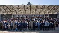 Soldaten und Zivilisten haben sich auf einer Tribüne zum Gruppenfoto aufgestellt. 