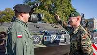 Zwei Soldaten stehen vor einem Panzer und unterhalten sich.