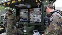 Zwei Soldaten arbeiten an einem Satellitensystem
