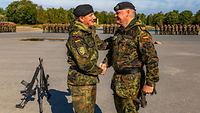 Zwei Soldaten schütteln sich auf dem Appellplatz vor den angetretenen Soldaten die Hände.