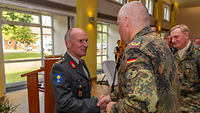 Ein deutscher Soldat zeichnet einen niederländischen Soldaten aus und gratuliert ihm mit Händedruck.