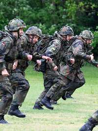 Soldatinnen und Soldaten rennen über eine Wiese