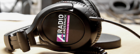 Radio Andernach Kopfhörer Kopfhörer mit dem Radio Andernach Logo im Fokus. Sie liegen auf dem Tisch in einem Tonstudio.