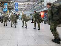 Ankunft Soldaten am Flughafen Mehrere Soldaten in Flecktarn Uniformmit Gepäck betreten die Halle eines Flughafens.