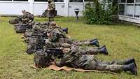 Soldaten liegen am Boden und üben an der Waffe.