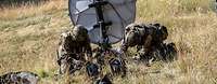 Zwei Soldaten bauen eine Satellittenschüssel auf