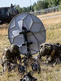 Zwei Soldaten bauen eine Satellittenschüssel auf