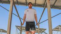 Ein Mann in Sportkleidung macht eine Stützübung an einem Barren