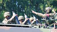 Drei Soldaten halten jeweils eine Mörsergranate in die Laufmündung. Der Ausbilder gibt Anweisungen dazu.