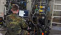 Soldat sitzt an an einem Laptop.