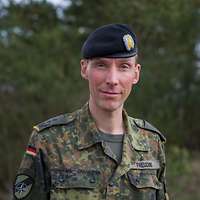 Ein Soldat mit einem schwarzen Barett schaut direkt in die Kamera.