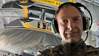 Porträtaufnahme eines Soldaten in Flecktarnanzug und großen Kopfhörern.