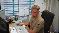 Ein Soldat sitzt an seinem Arbeitsplatz