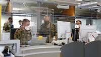 Drei Soldaten sitzen hinter einem Flughafenschalter