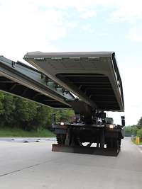 Trägerfahrzeug vom Typ Leopard 2 fährt die 14 Meter lange Gefechtsfeldbrücke aus Brückenlegepanzer mit ausgefahrener Brücke