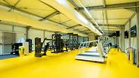 Verschiedene Fitnessgeräte in einem Gebäude aus Containermodulen.